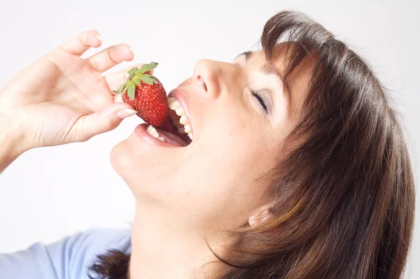 在花园里吃草莓的年轻女人 — 图库照片