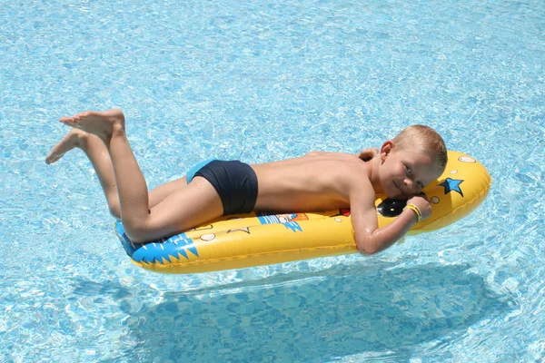 男孩躺在游泳池的气垫上 — 图库照片