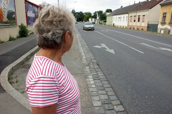 Una Vecchia Aspetta Una Macchina Passaggio Una Strada — Foto Stock