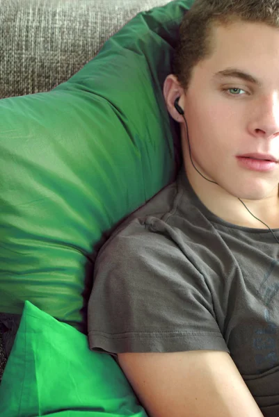 穿着绿色衬衫躺在床上的年轻人 — 图库照片