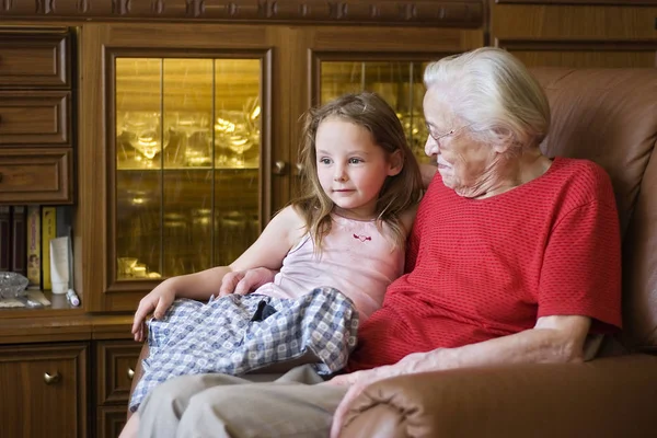 祖母と孫娘が家でソファに座って — ストック写真