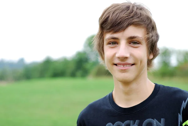Χαμογελαστός Νεαρός Άνδρας Στέκεται Ένα Πράσινο Γκαζόν Στο Καλοκαιρινό Πάρκο — Φωτογραφία Αρχείου