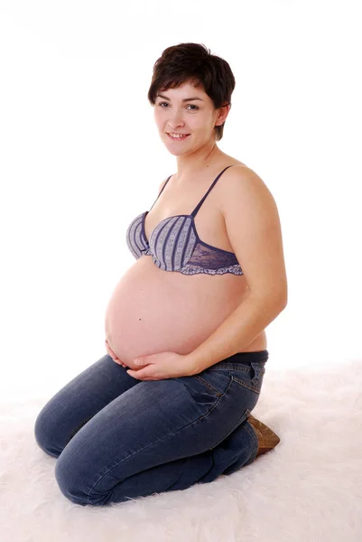 おなかを抱えて床に座る妊婦さん — ストック写真