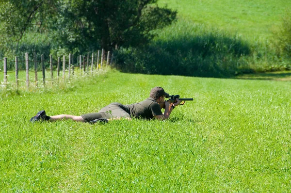 草の中に銃を持ったカモフラージュの男が — ストック写真