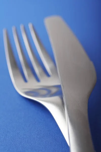 在蓝色背景上关闭叉子和勺子 — 图库照片