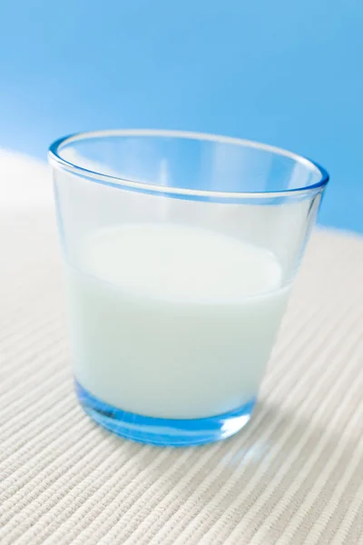 蓝色底色上装满牛奶的杯子 — 图库照片