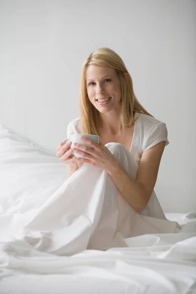 Жінка Сидить Ліжку Білими Простирадлами Тримаючи Чашку — стокове фото