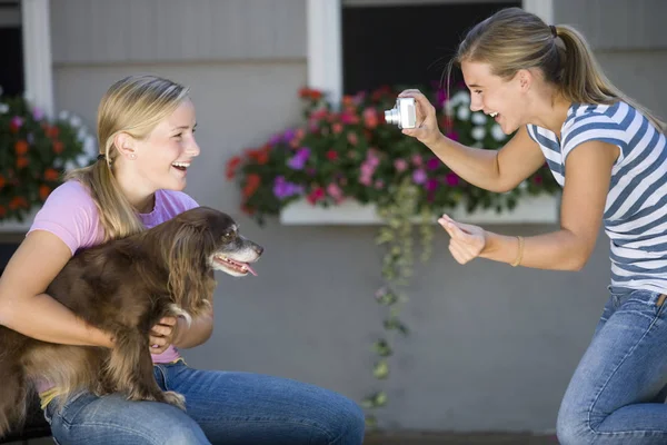 ティーン女の子Posesとともに彼女の犬一方親友取ります写真とともにデジタルカメラ — ストック写真