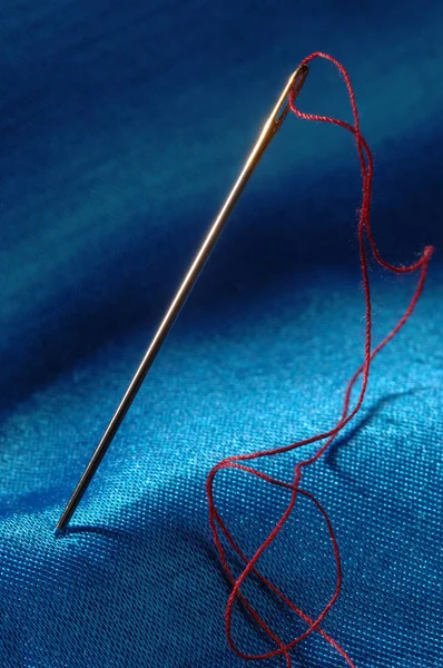 needle and thread on blue background