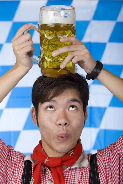 Asian man having Oktoberfest beer stein  head and looks surprise