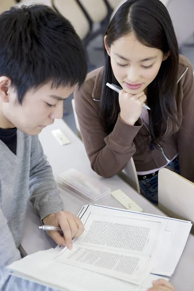 アジア系の若い女性と学生が教室で勉強していて — ストック写真