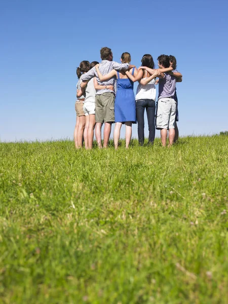 A group of people huddle in a field. Vertically framed shot.