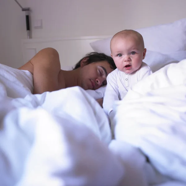Pai Dormindo Cama Com Bebê Acordado Sentado Seu Lado Formato — Fotografia de Stock