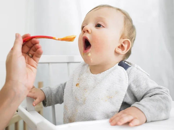 大人に食べさせられるハイチェアの赤ん坊 横枠のショット — ストック写真