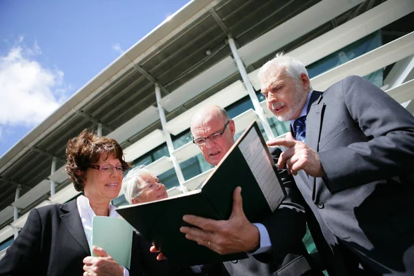 Portrait of a group of seniors read the documents to a modern building