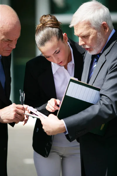 Young woman reading document with two older men in suits