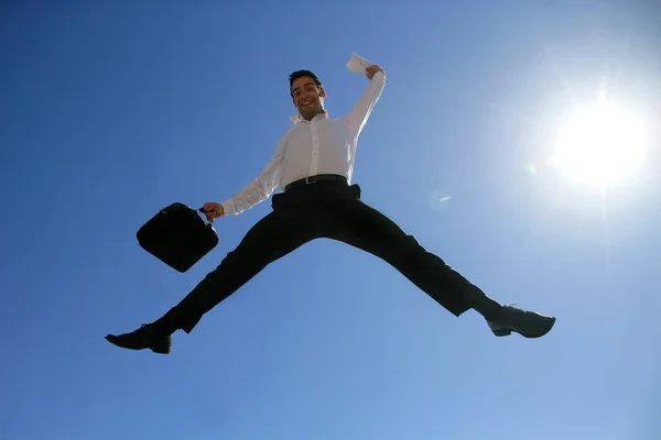 Smiling man in suit with briefcase jumping in the air face