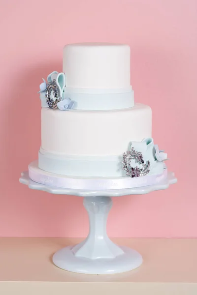 ピンクの背景のケーキスタンドには2層のケーキが座っています 縦枠のショット — ストック写真