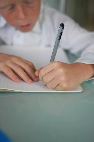 Menino Escrevendo Caderno Com Uma Caneta Preta — Fotografia de Stock