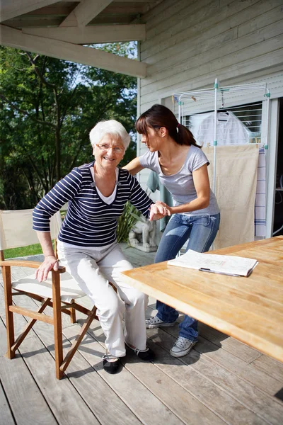 Young woman helping a senior woman to rise