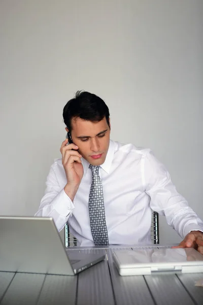 Porträtt Man Som Sitter Bakom Skrivbordstelefon Med Mobiltelefon — Stockfoto