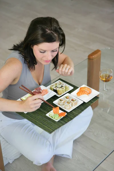 Frau Sitzt Auf Dem Boden Und Isst Sushi Mit Essstäbchen — Stockfoto