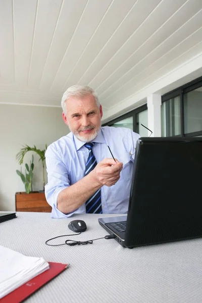 Senior Man Zit Achter Een Bureau Voor Een Laptop — Stockfoto