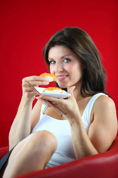 Portret Kobiety Siedzącej Krześle Jedzącej Sushi Czerwonym Tle — Zdjęcie stockowe