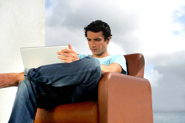 Focusing Man Seated Armchair Terrace Laptop Sea Profile — Stock Photo, Image