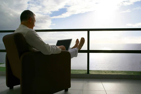 Man Sitter Fåtölj Terrassen Med Laptop Framför Havet Tillbaka — Stockfoto