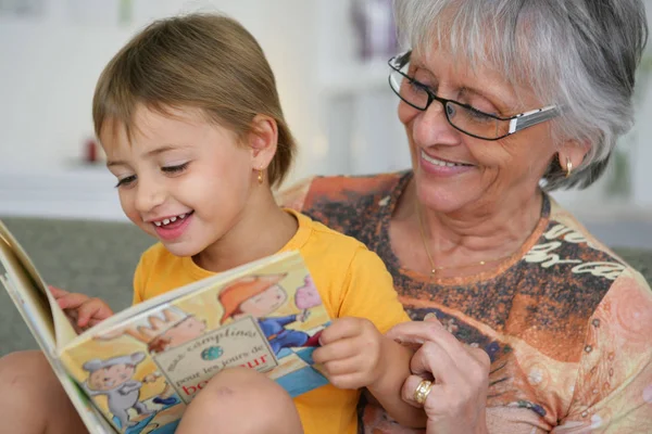 年配の女性と笑顔の女の子の肖像子供のための本を読んで — ストック写真