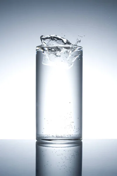 Glas Gefüllt Mit Spritzwasser Auf Reflektierender Oberfläche — Stockfoto