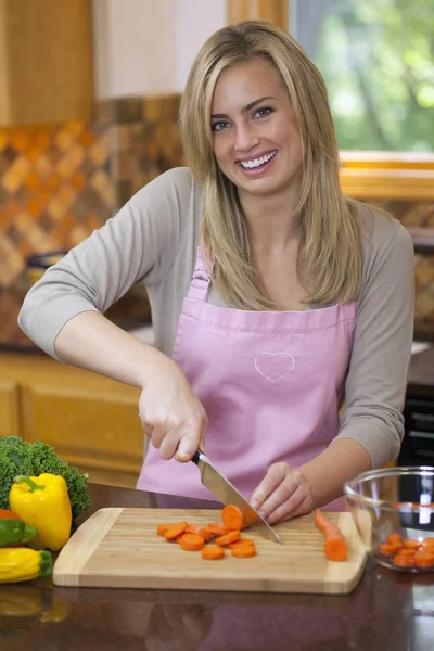 Μια Νεαρή Γυναίκα Κόβει Καρότα Στην Κουζίνα Της Και Χαμογελάει — Φωτογραφία Αρχείου