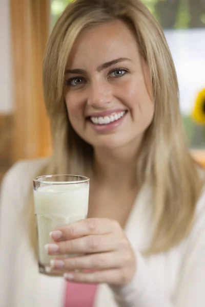 Μια Νεαρή Γυναίκα Κρατάει Ένα Ποτήρι Γάλα Και Χαμογελάει Στην — Φωτογραφία Αρχείου