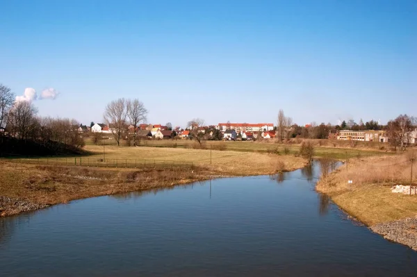 平静的河流与地平线上的村庄 — 图库照片