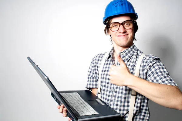 灰色の背景にノートパソコンを持つヘルメットの若い男 — ストック写真