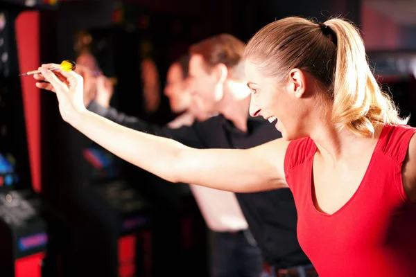 group of friends playing darts