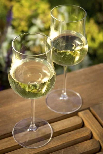 室外环境中的木制桌子上站着两杯白葡萄酒 垂直射击 — 图库照片