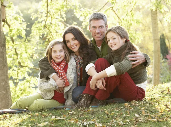 Family Group Relaxing Outdoors In Autumn Landscape