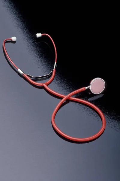 Červený Stetoskop Leží Černém Reflexním Povrchu Svislý Výstřel — Stock fotografie