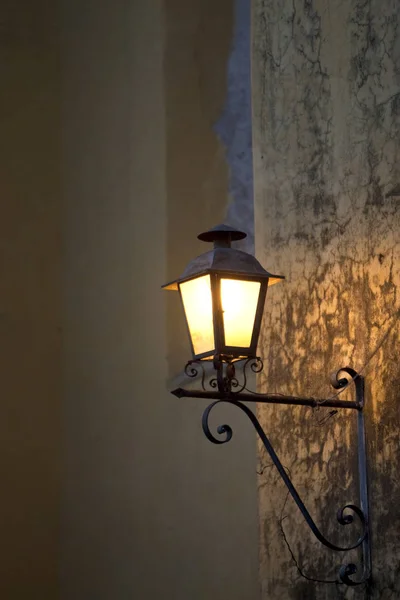コンクリートの壁に取り付けられたスペインスタイルのランプが夕方に成長します — ストック写真