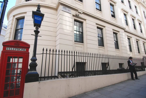 男は赤い電話ボックスでロンドンの通りに立っている — ストック写真