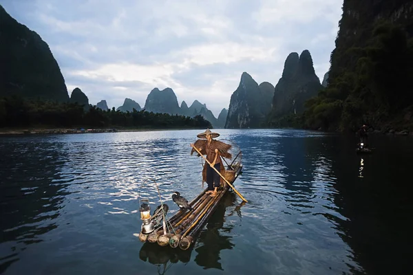 Fisherman standing on a wooden raft in a river, Li River, XingPing, Yangshuo, Guangxi Province, China