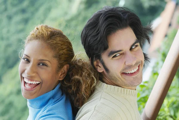 Close-up of a young couple back to back and smiling