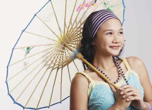 Close-up of a young woman holding a parasol and smiling