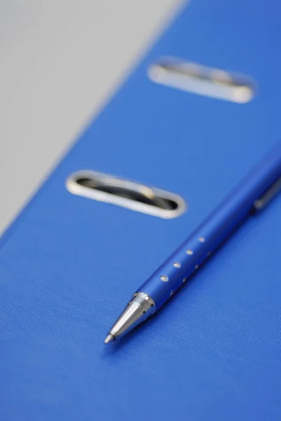 Close-up of a ballpoint pen on a ring binder