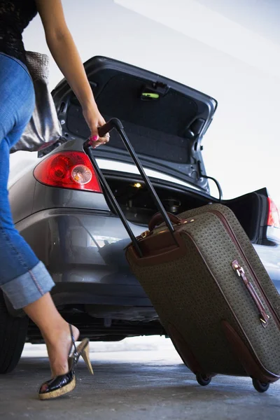 Young woman unloading luggage from car