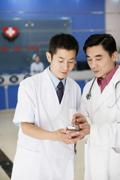 Close-up of two male doctors looking at a personal data assistant