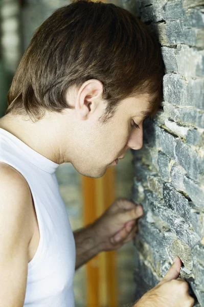 Side profile of a young man banging his head against a wall