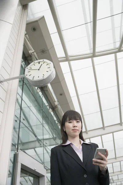 Low angle view of a businesswoman holding a personal data assistant and waiting at an airport lounge